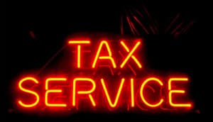 A neon sign reads "Tax Service"