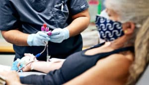 A woman gives blood as a health care worker handles vials of blood