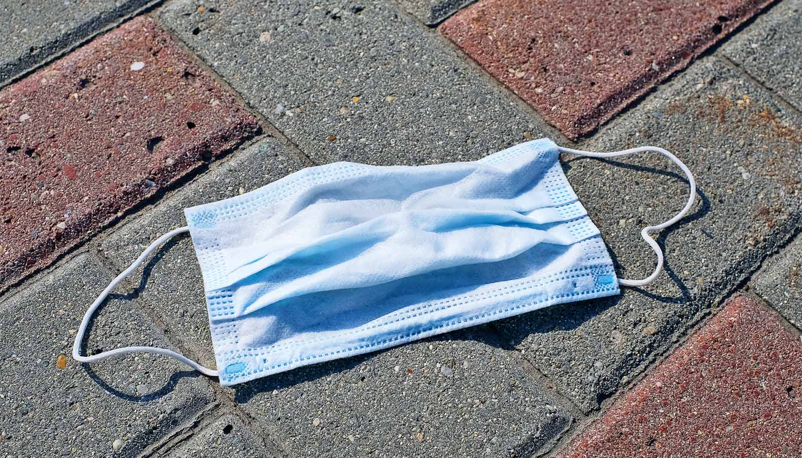 A medical mask laying on a city sidewalk made of bricks