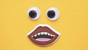 googly eyes and sticker mouth on yellow paper