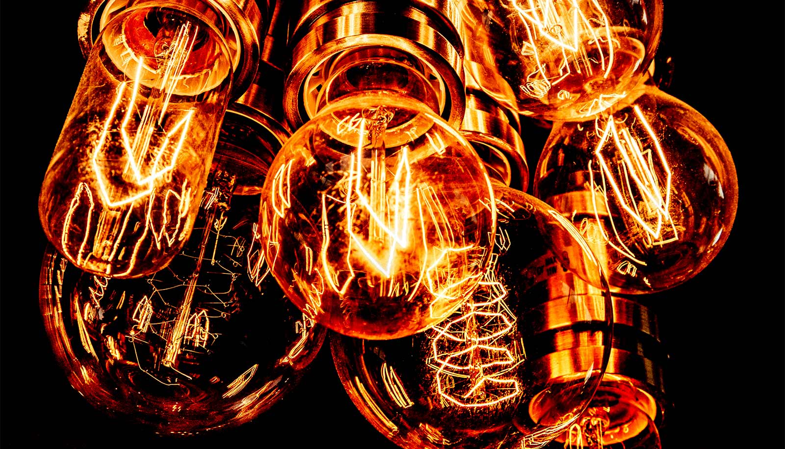 A group of lightbulbs glowing orange against a black background.