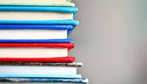 A stack of books with colorful covers against a gray background.