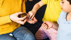 A mother gives her two children dietary supplement vitamin pills.