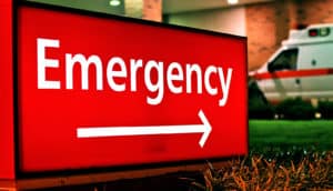 A red light-up sign outside the hospital reads "Emergency" in white letters