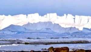 White, icy cliffs stand against a bright blue sky.