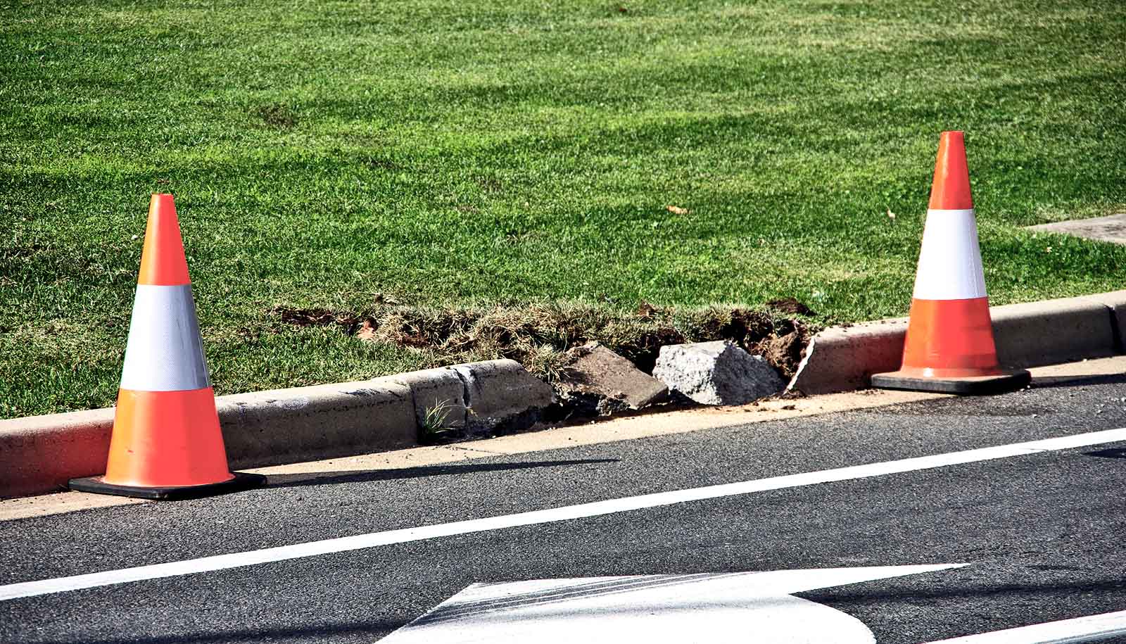 two cones next to broken curb