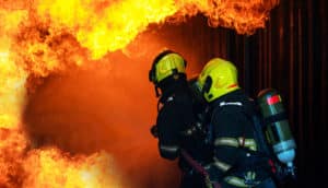 two firefighters move toward flames