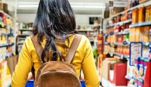 A young woman walks pushes a cart through a grocery store.