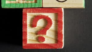 A child's wooden block has a red question mark on it.