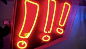 A neon sign shows three red exclamation points.