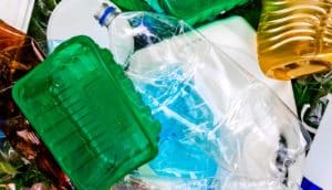 Plastic trash that includes a green plastic tub and clear plastic bottles.