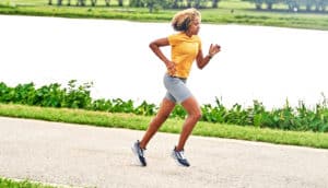A woman runs on a path next to water.