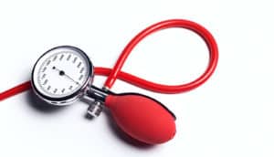 A blood pressure cuff's red tube, pump, and gauge..