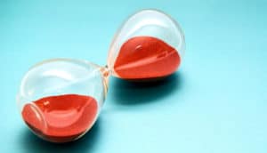 An hourglass filled with red sand sits on its side so no sand moves.