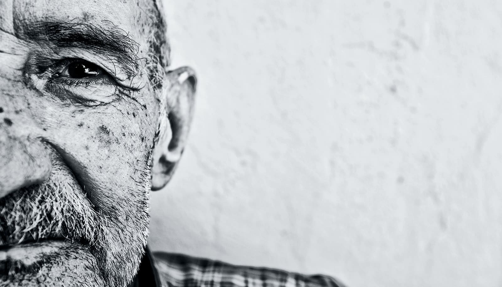 An older man looks into the camera with just half his face in frame.