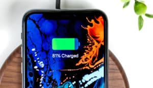 A phone is charging on a wireless charging pad, with the green battery bar filling up on screen.