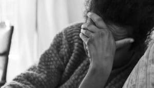 slumped person holds hand over face in gesture of sadness