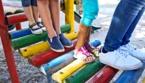 Kids stand in a line on playground equipment.