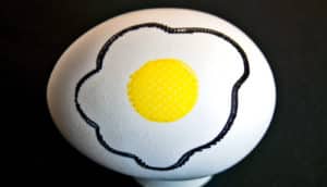 A white egg with a cooked egg drawn on it showing a yolk and white.