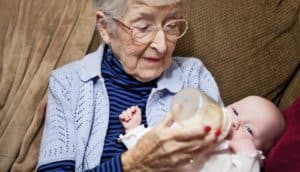 elderly adult feeds baby a bottle