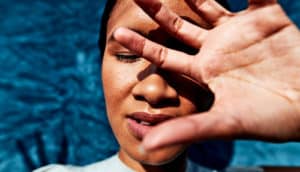 A woman puts her hand up to block the sun from her face.