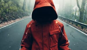 unseen figure in coat stands on gloomy road with string of lights across shoulders