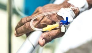 A hospital patient's hand with an IV running into their arm.