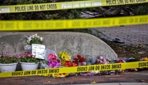 police tape in front of flowers in memorial