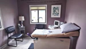 soft purple walls in clinic room with ultrasound machine, chairs, and exam table. Maya Angelou quote on wall "But they will never forget how you made them feel"