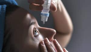 person drips eyedrops into eye