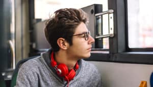 A young man riding a bus looks out the window.