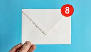 hand holds white envelope with red 8 on the corner - email concept