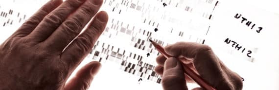 A criminologist examines a black and white readout of DNA data.