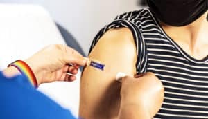 A health worker places a band-aid over a flu shot injection site.
