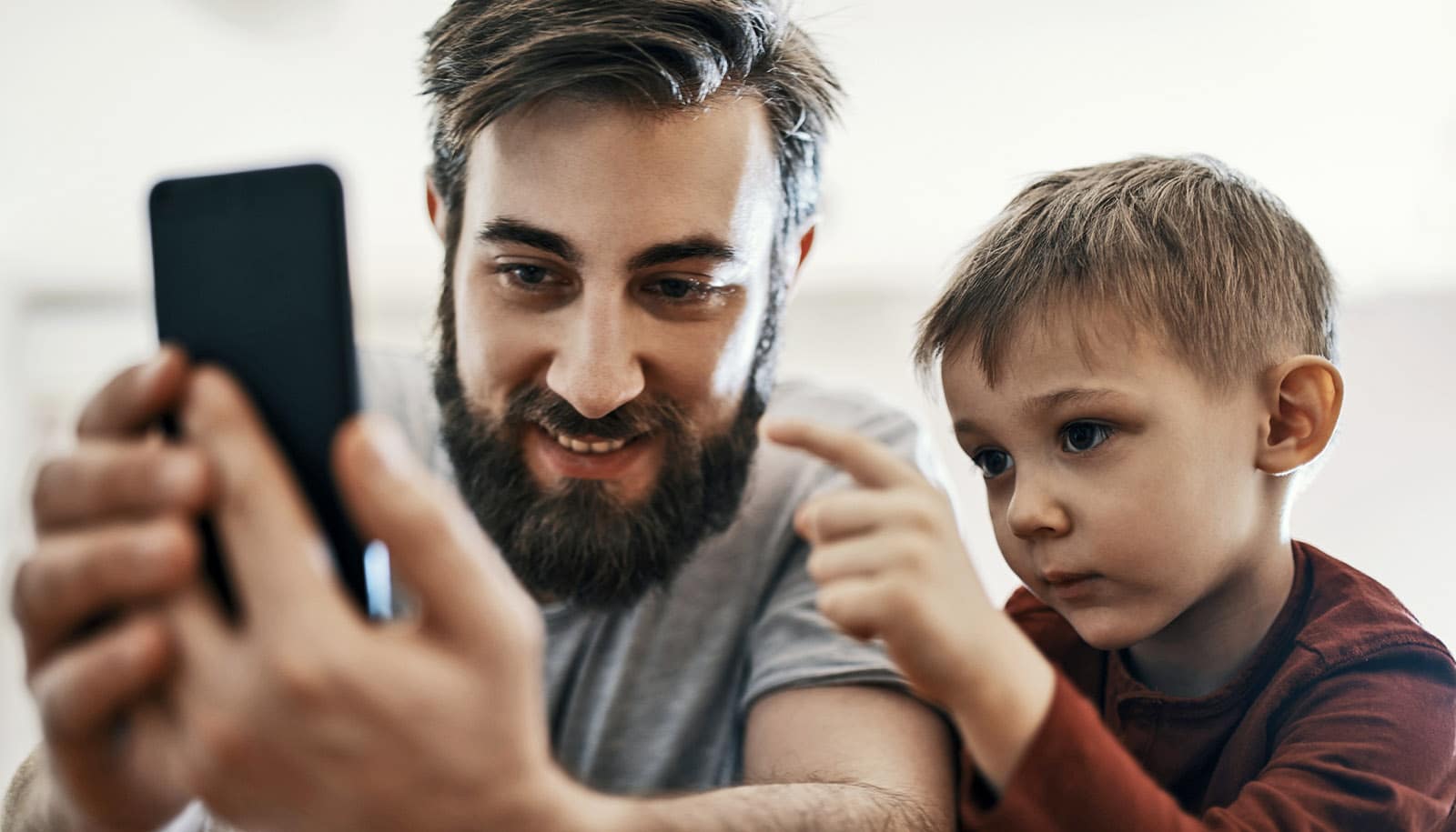 child points to smartphone in adult's hands