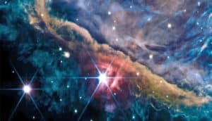 Two bright stars shine through the blue and orange dust clouds of the Orion Nebula.