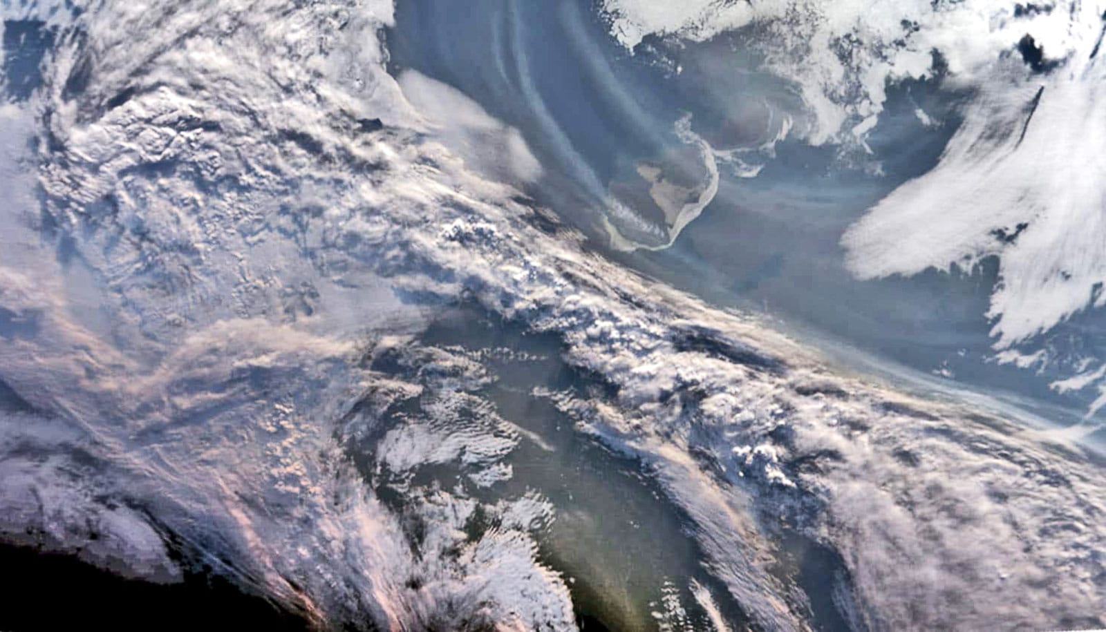 Smoke curls over the arctic ocean.