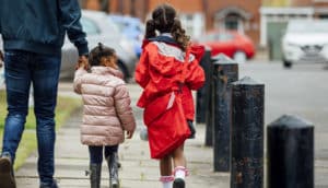 rear view of adult and two kids walking on sidewalk