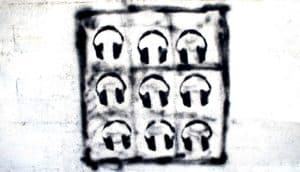 Nine boxes with headphones in them painted in black on a white wall.