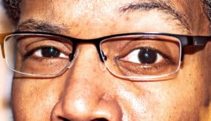 A man wearing glasses looks at the camera with one eyebrow raised slightly.