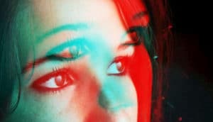 A young woman's face shown in blue light and then superimposed over it in red.