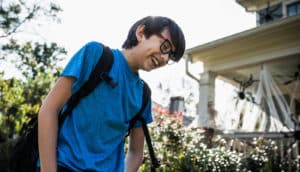 laughing teen kid in backpack and glasses outdoors