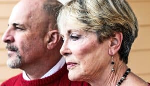 A man and woman stand side by side as she looks downward.