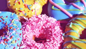 Colorful frosted donuts with sprinkles on them.