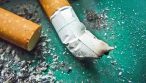 cigarette buts in green ashtray