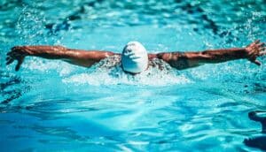 A swimmer does the butterfly stroke in an Olympic pool.