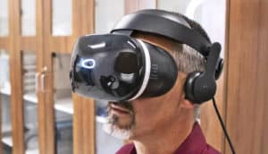 A researcher wears a black virtual reality headset with headphones.