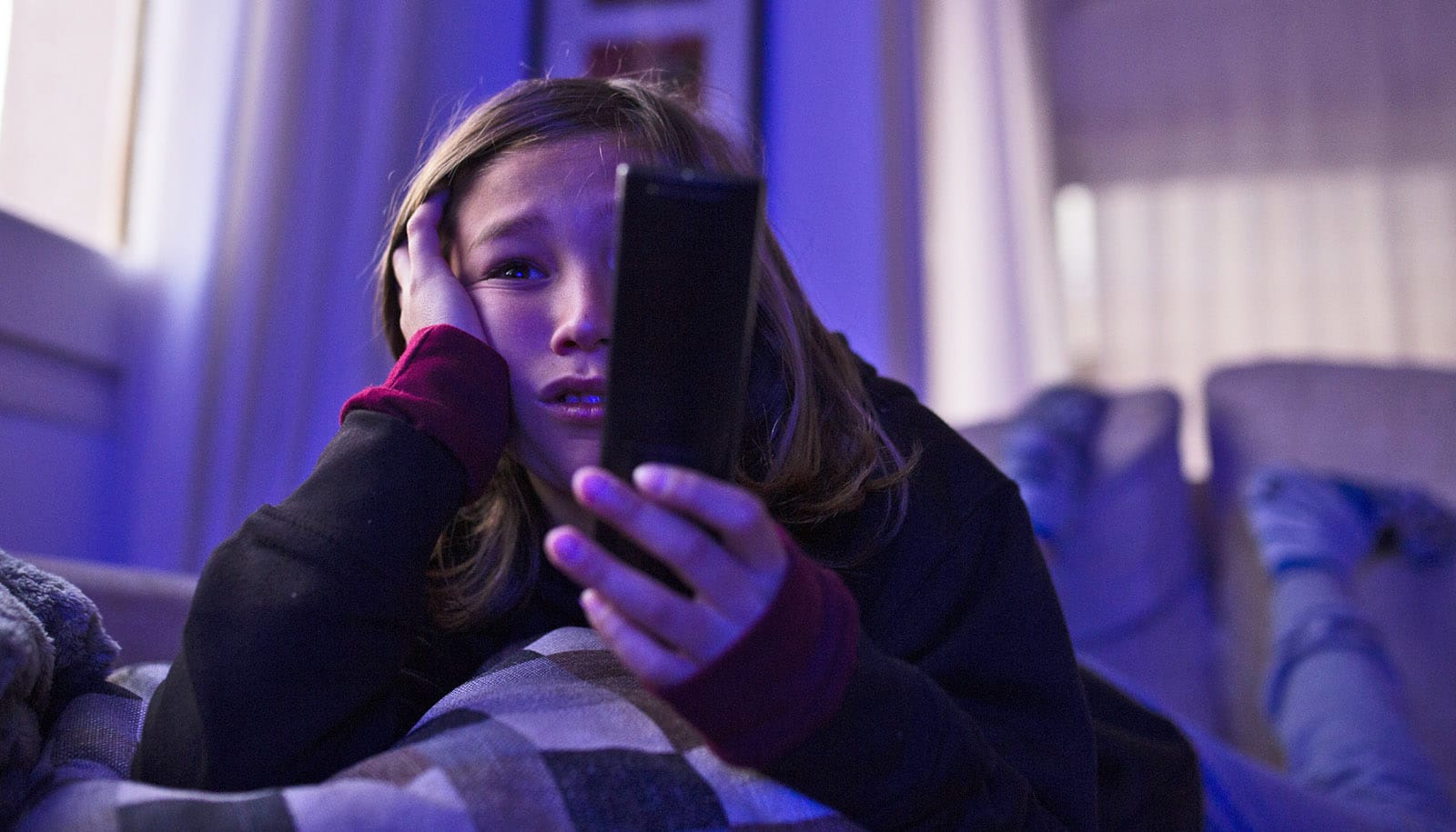 teen looks upset while holding remote in dim room
