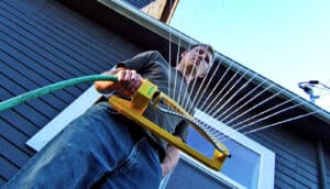 from below, person holds sprinkler in front of house