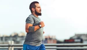 A man jogs along a bridge while listening to music.